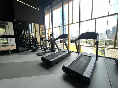 a gym with several tread machines in a room with windows at Opus Residences 2 Bedroom Apartment in Kuala Lumpur