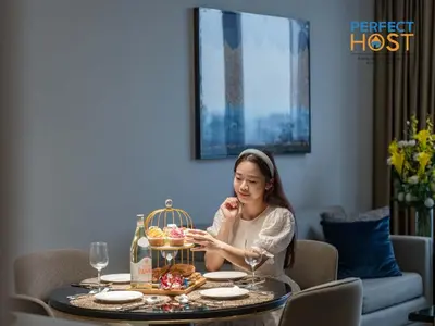 a woman sitting at a table with a plate of food at Pavilion Ceylon Hill Suites, Bukit Bintang by Perfect Host in Kuala Lumpur