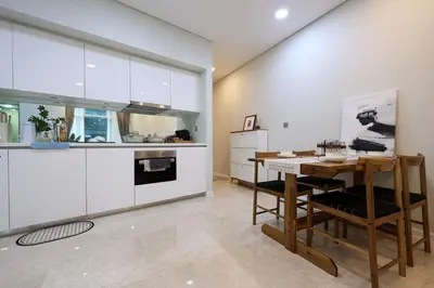 a kitchen with white cabinets and a wooden table at Sky Suites KLCC By Calm Sojourn in Kuala Lumpur