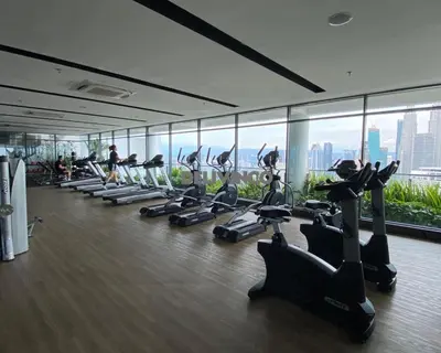 a gym with a row of treadmills and people exercising at Stylish AeroSpace Theme 1BR in KL City Center in Kuala Lumpur