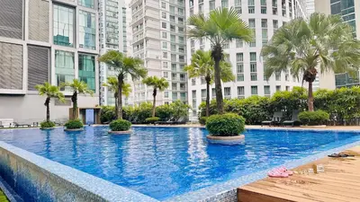 a large swimming pool with palm trees and buildings at Soho Suites KLCC By Grand KL in Kuala Lumpur