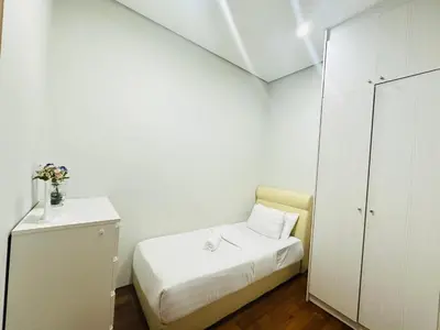 a small bedroom with a bed and a white cabinet at Soho Suites KLCC By Grand KL in Kuala Lumpur