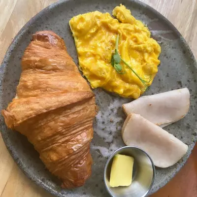 a plate of food with eggs and bread and cheese at Societe Suites By iHost Global in Kuala Lumpur