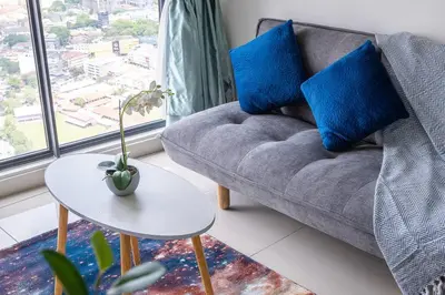 a living room with a couch and a table with blue pillows at Continew 1BR High TRX Mall King Bed 100Mbps Wi-Fi in Kuala Lumpur