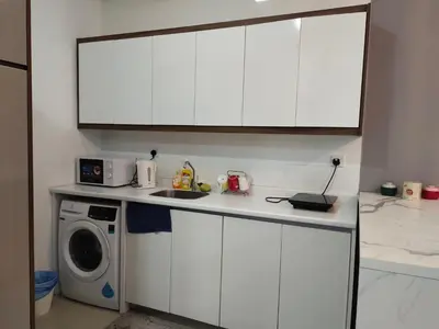 a kitchen with white cabinets and a washing machine at Arte plus by sweet home studio in Kuala Lumpur