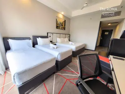 a hotel room with two beds and a chair at The Roma at Dang Wangi Kuala Lumpur in Kuala Lumpur
