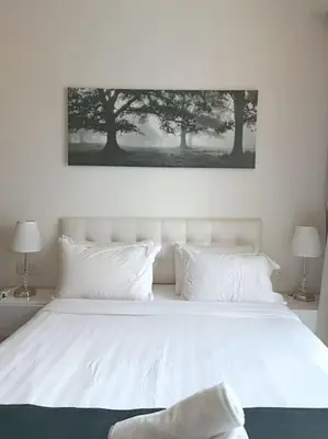 a white bed with white pillows and a picture above it at RM238 Bukit Bintang Balcony Studio Infinty Pool in Kuala Lumpur