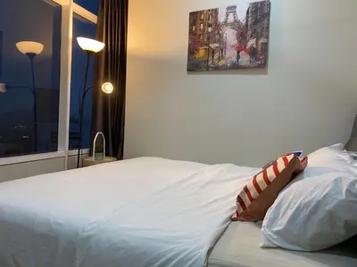a bedroom with a white bed with a painting on the wall at sky suite klcc in Kuala Lumpur
