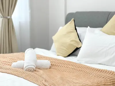 a rolled up towel on top of a bed at MH Maison by Manhattan Group in Kuala Lumpur
