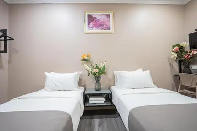 two beds in a room with a vase of flowers at HOTEL 28 RAPID in Kuala Lumpur