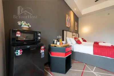 a bedroom with a bed and a tv and a refrigerator at Maison 101 Dang Wangi Kuala Lumpur KLCC in Kuala Lumpur