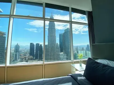 a bedroom with a view of a city from a window at Sky Suite @ KLCC - 3BR KLCC View in Kuala Lumpur