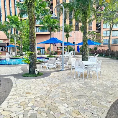 a patio with tables and chairs and palm trees at Peak Suites At Times Square in Kuala Lumpur