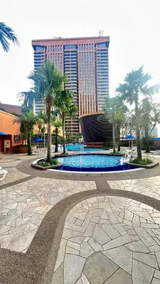 a swimming pool with palm trees and a building at Peak Suites At Times Square in Kuala Lumpur