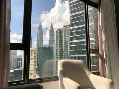 a white chair sitting in front of a window at 8 Kia Peng Suites KLCC by Luna in Kuala Lumpur