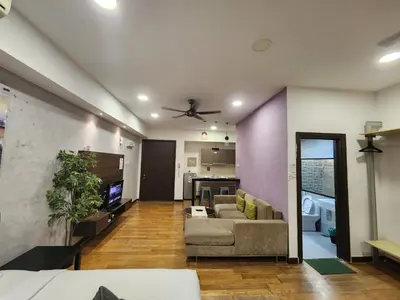 a living room with a couch and a kitchen at Regalia Suites Kuala Lumpur KLCC in Kuala Lumpur