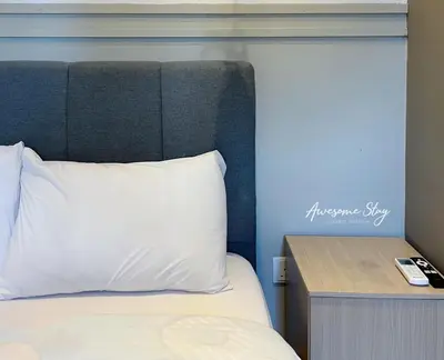 a bed with a white pillow and a wooden table at Colony By Infinitum in Kuala Lumpur