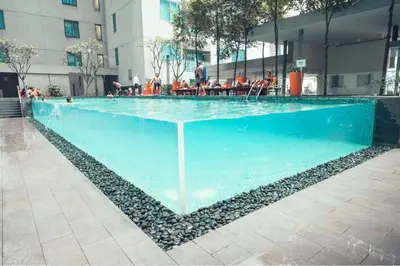 a large blue pool with people sitting around it at Mercu Summer Suites Klcc by Luxe Residence in Kuala Lumpur