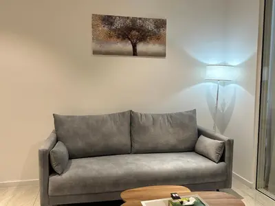 a couch in a living room with a tree on the wall at Quill Suites KLCC in Kuala Lumpur