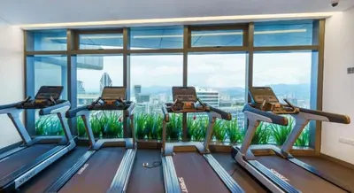 a gym with three treadmills and a large window at Eaton Suites KLCC Kuala Lumpur in Kuala Lumpur