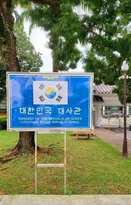 a blue sign in a park next to a tree at The Nova by The City Collection II in Kuala Lumpur