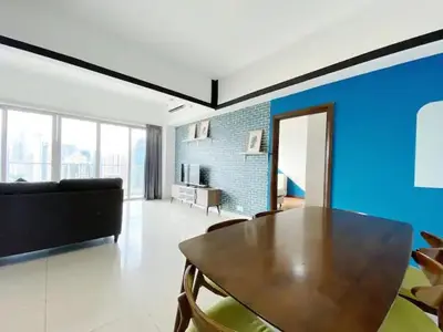 a living room with a wooden table and a blue wall at Regalia Resident by Great Stay in Kuala Lumpur