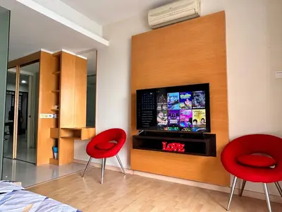 a living room with two red chairs and a tv at Private Jacuzzi Suite - Pertama Residency in Kuala Lumpur
