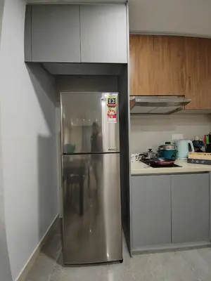 a stainless steel refrigerator in a kitchen with wooden cabinets at The Ooak Mont Kiara 33A# Main Street Sunway 163#1 bedroom 1-2Pax in Kuala Lumpur