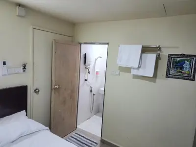 a bathroom with a shower and a toilet and a bed at 24Seven Guesthouse in Kuala Lumpur