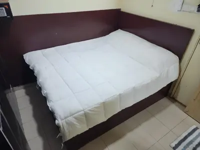 a small bed with a white blanket on it at 24Seven Guesthouse in Kuala Lumpur