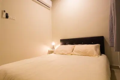 a bedroom with a bed with white sheets and a lamp at KL 9Pax 10Mins to Sentul LRT, Batu Caves, MCD (Zena Suites) in Kuala Lumpur
