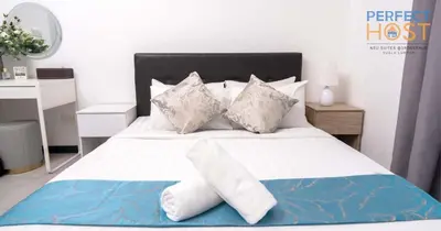 a bedroom with a bed with white sheets and pillows at Neu Suites @ 3rdNvenue by Perfect Host in Kuala Lumpur