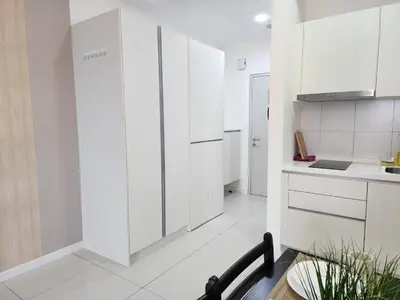 a white kitchen with white cabinets and a table at Chambers Residences Suites KLCC in Kuala Lumpur