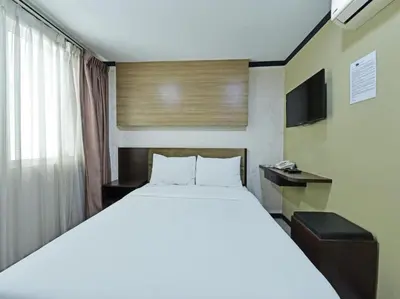 a bedroom with a large white bed and a television at One Enigma Hotel in Kuala Lumpur