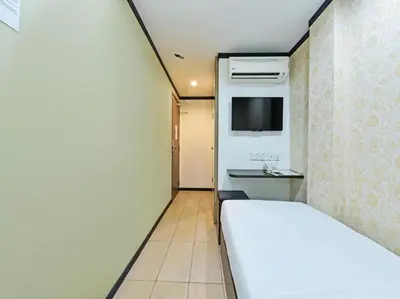 a hotel room with a bed and a tv at One Enigma Hotel in Kuala Lumpur
