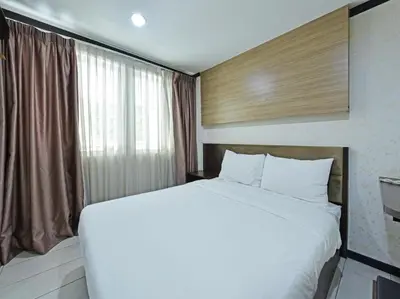 a large white bed in a room with a window at One Enigma Hotel in Kuala Lumpur