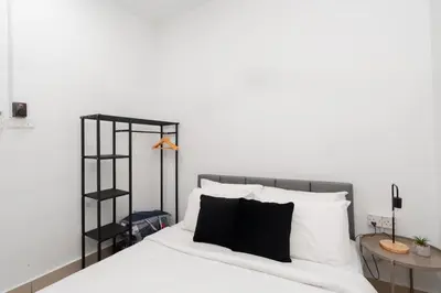 a bedroom with a bed with white sheets and a black shelf at Razak City Residence by Lisa Homestay in Kuala Lumpur