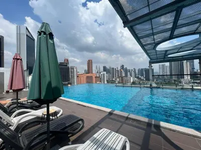 a swimming pool with chairs and umbrellas on a building at D'Majestic Kuala Lumpur By Luxe Home in Kuala Lumpur