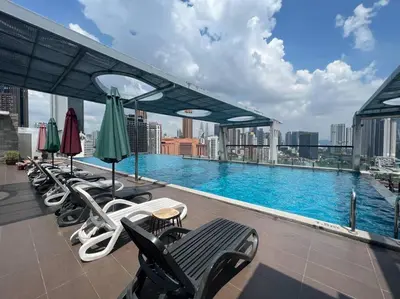 a pool on the roof of a building with chairs and umbrellas at D'Majestic Kuala Lumpur By Luxe Home in Kuala Lumpur