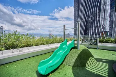 a playground with a green slide on the grass at Arte Mont Kiara Free Parking, Kuala Lumpur in Kuala Lumpur