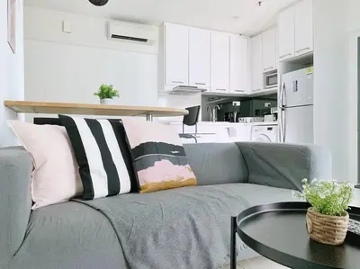 a gray couch with pillows and a table in a kitchen at Mercu Summer Suites KLCC 2BR Pastel Rose in Kuala Lumpur