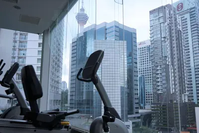 a gym with a view of a city with tall buildings at Ramada Suites by Wyndham Kuala Lumpur City Centre in Kuala Lumpur