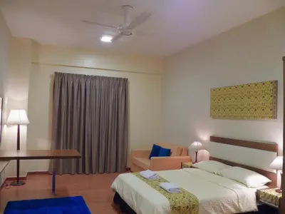 a hotel room with a bed and a chair and a table at Maytower Apartment in Kuala Lumpur