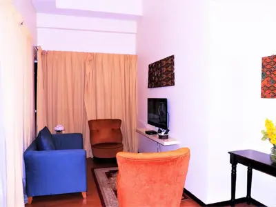 a living room with a blue chair and a television at Maytower Apartment in Kuala Lumpur
