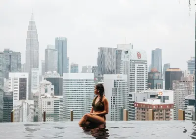 a woman sitting in a infinity pool overlooking a city at Ceylonz Suite Kuala Lumpur Bukit Bintang in Kuala Lumpur