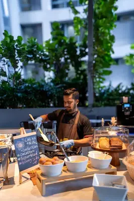 a man in an apron preparing food on a table at Ceylonz Suite Kuala Lumpur Bukit Bintang in Kuala Lumpur