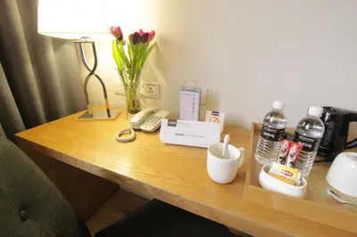 a desk in a hotel room with a telephone and flowers at de King Hotel KLCC in Kuala Lumpur