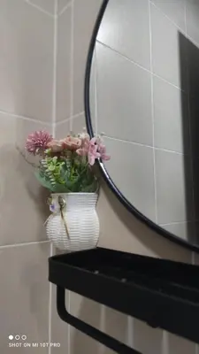 a vase with flowers on a shelf next to a mirror at HaNi Homestay KL in Kuala Lumpur