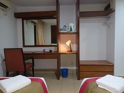 a room with two beds and a desk and a mirror at Hotel Seri Putra in Kuala Lumpur