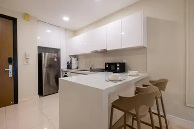 a kitchen with white cabinets and bar stools at The Element Ampang in Kuala Lumpur